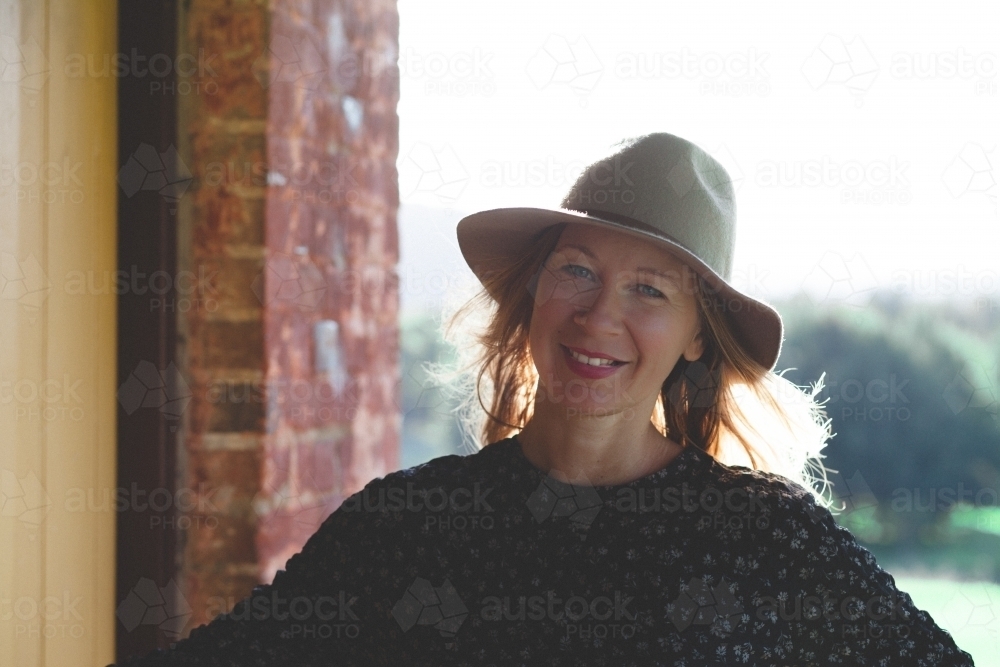 Woman smiling on the porch of a house in the country - Australian Stock Image