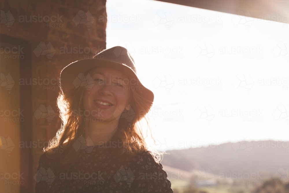 Woman smiling on the porch of a house in the country - Australian Stock Image