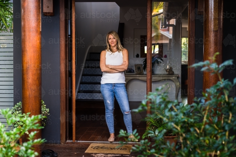 woman standing at the front door of her home - Australian Stock Image