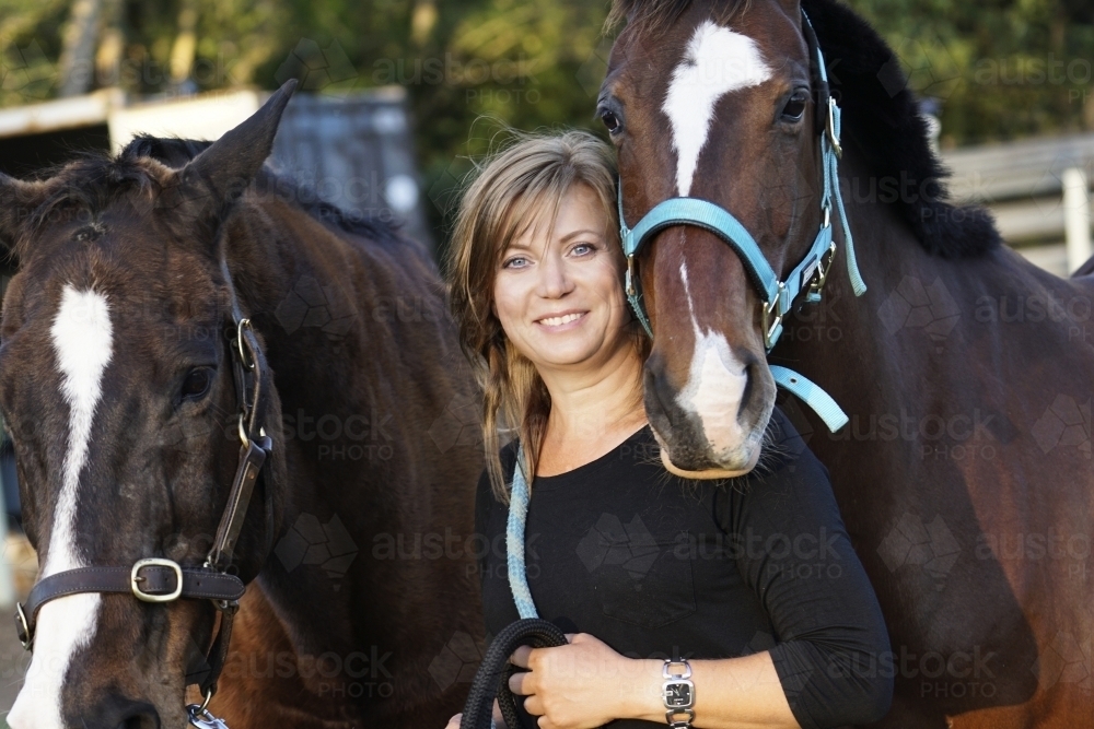 Woman standing between two horses - Australian Stock Image