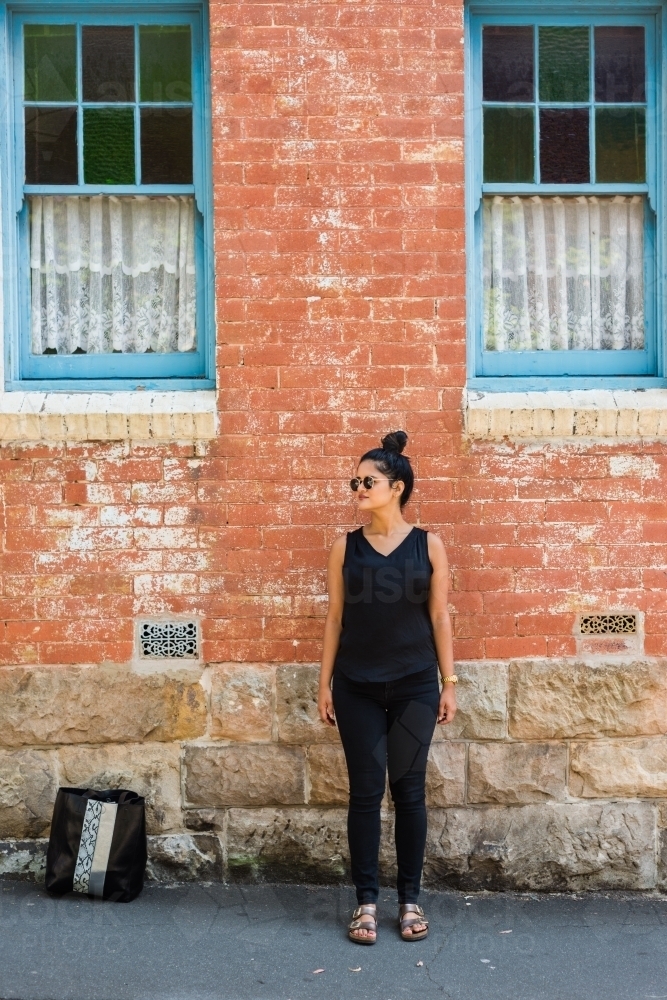 woman standing on the footpath in urban setting - Australian Stock Image