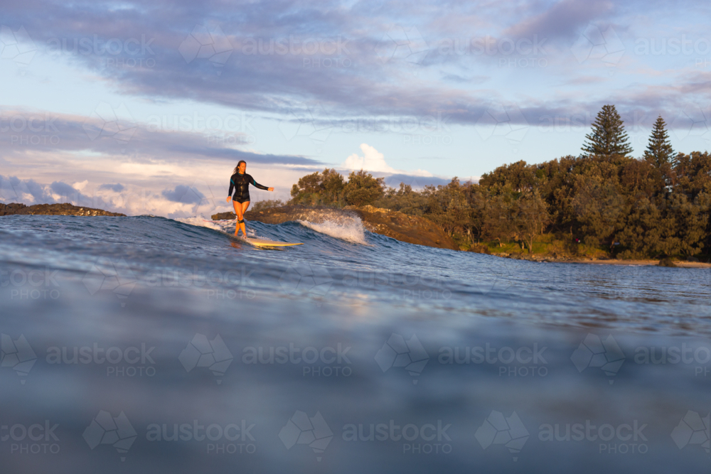 Woman surfing on an ocean wave a Malibu at sunset - Australian Stock Image