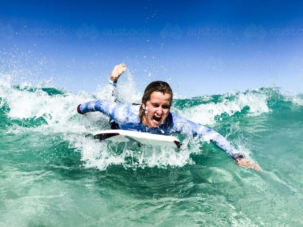 Woman surfing wave on a boogie board in clear ocean - Australian Stock Image