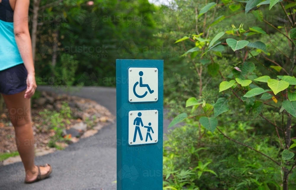 Woman walking past signage on a walking track - Australian Stock Image