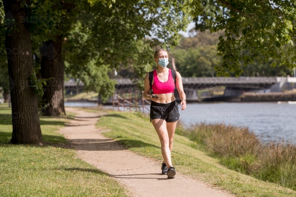 Woman Wearing a Face Mask Walking by the Yarra - Australian Stock Image