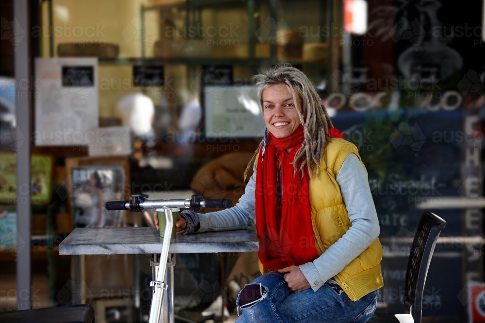 Woman with dreadlocks at cafe with electric scooter - Australian Stock Image