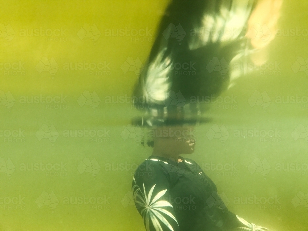 Womans upper body submerged underwater in river with reflection - Australian Stock Image