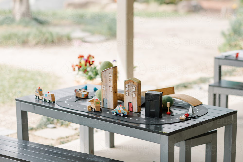 Wooden car toy and buildings a street concept setup on a table at childcare centre - Australian Stock Image