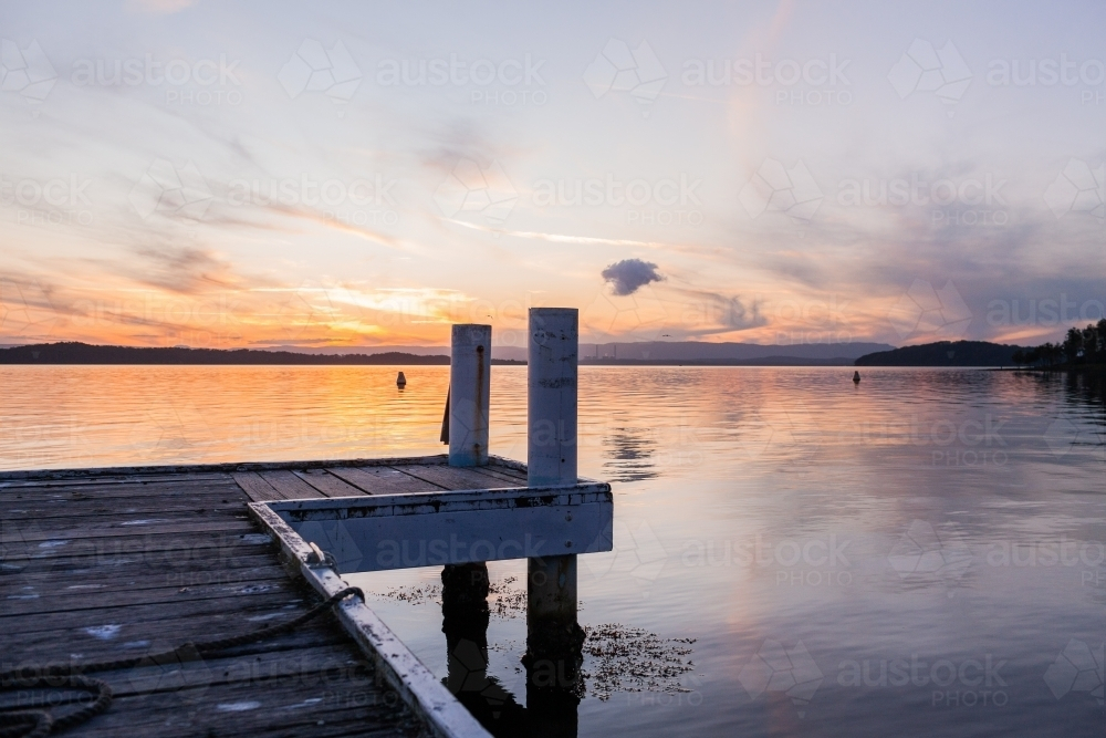 wooden jetty posts in lake water in pastel dusk light Cams Wharf, Newcastle, NSW, Australia - Australian Stock Image