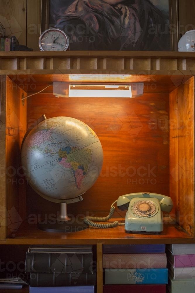 World globe and rotary telephone in lighted alcove - Australian Stock Image