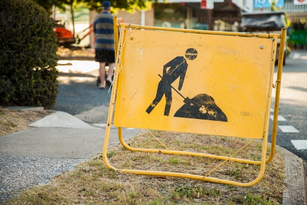 Yellow digging road work sign near construction site on footpath - Australian Stock Image