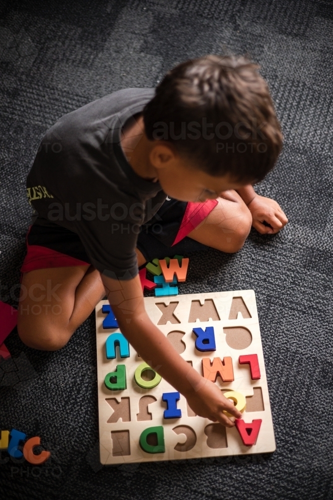 Young Aboriginal boy doing a letter puzzle - Australian Stock Image