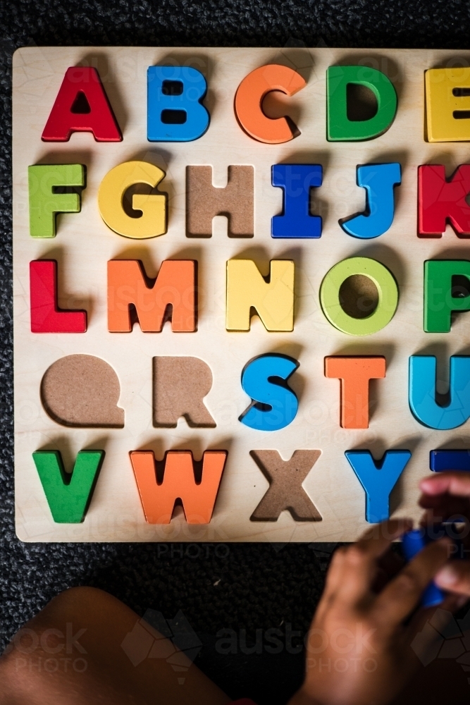 Young Aboriginal boy doing a letter puzzle - Australian Stock Image