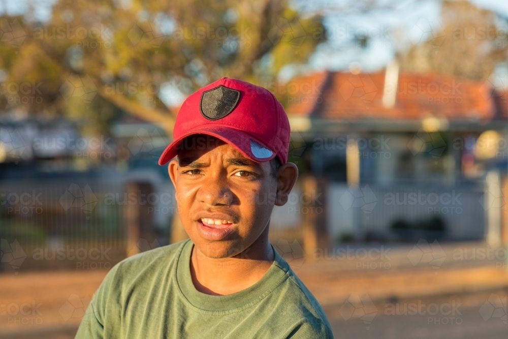 Young aboriginal boy looking at camera outside house - Australian Stock Image