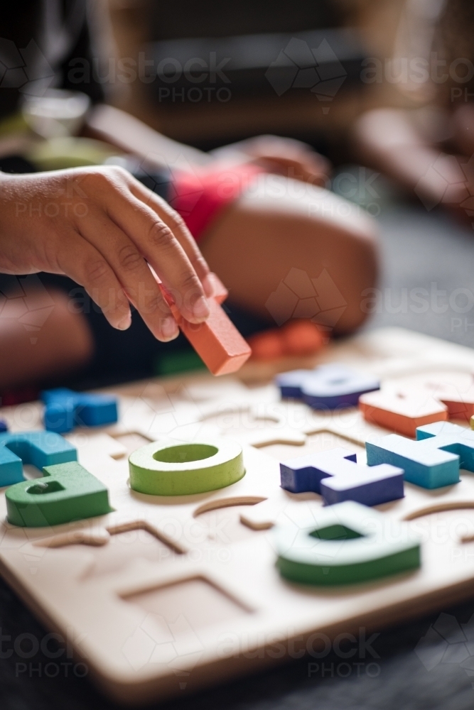 Young Aboriginal boy playing with alphabet letter puzzle pieces - Australian Stock Image