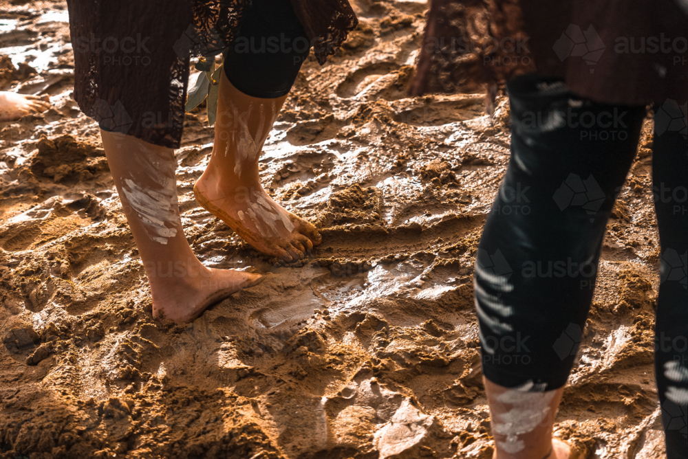 Young Aboriginal feet in muddy Corroboree circle - Australian Stock Image