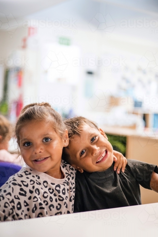 Young Aboriginal girl and boy hugging at preschool - Australian Stock Image