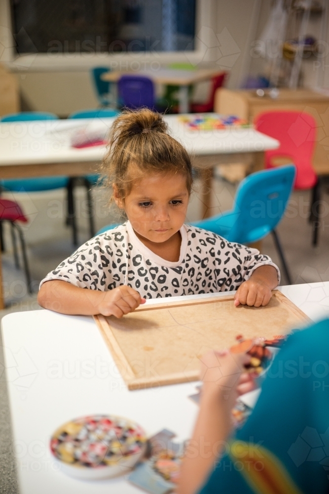 Young Aboriginal girl at preschool doing a puzzle - Australian Stock Image