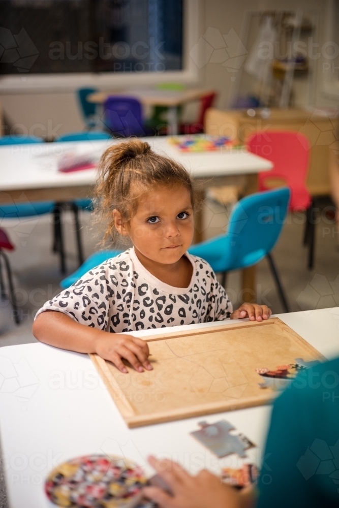 Young Aboriginal girl at preschool doing a puzzle - Australian Stock Image