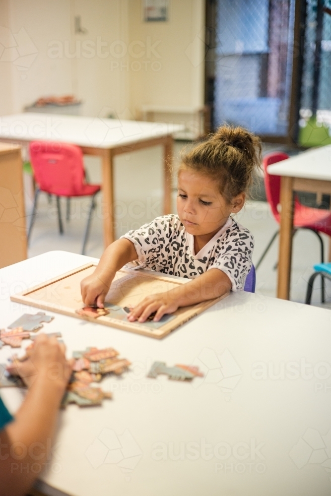 Young Aboriginal girl at preschool doing a puzzle - Australian Stock Image