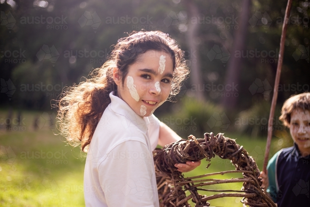 Young Aboriginal girl holding a wooden basket smiling at the camera - Australian Stock Image