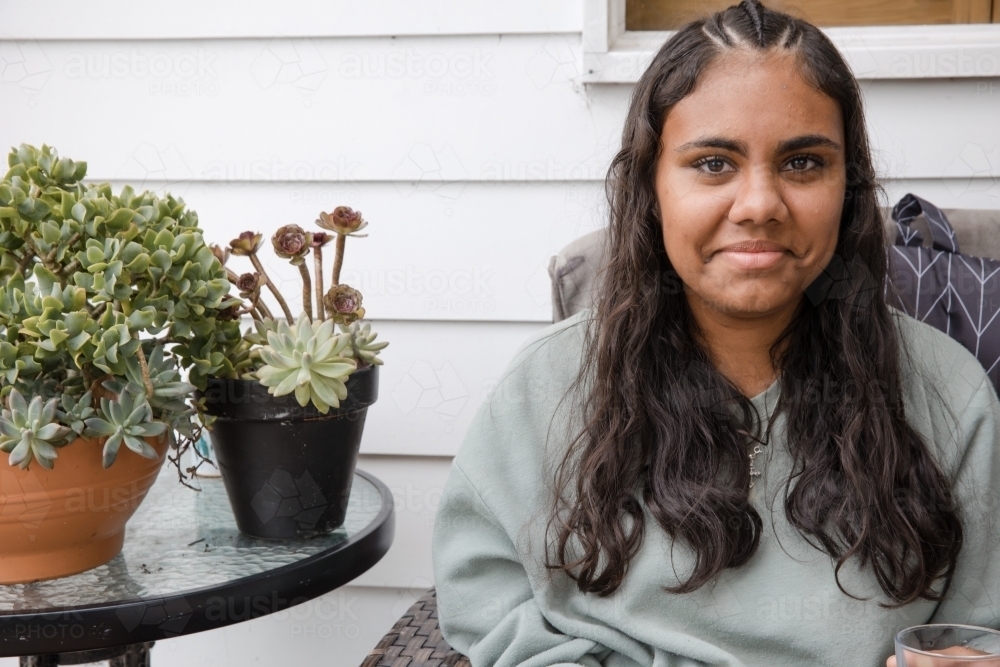 Young Aboriginal woman sitting on a couch outside - Australian Stock Image