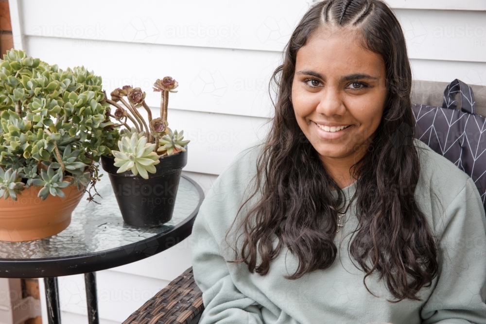 Young Aboriginal woman sitting on a couch outside - Australian Stock Image