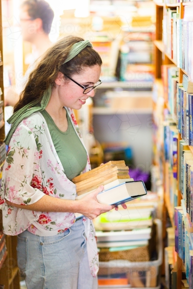 Young adult browsing the fantasy shelves of a second hand book shop - Australian Stock Image