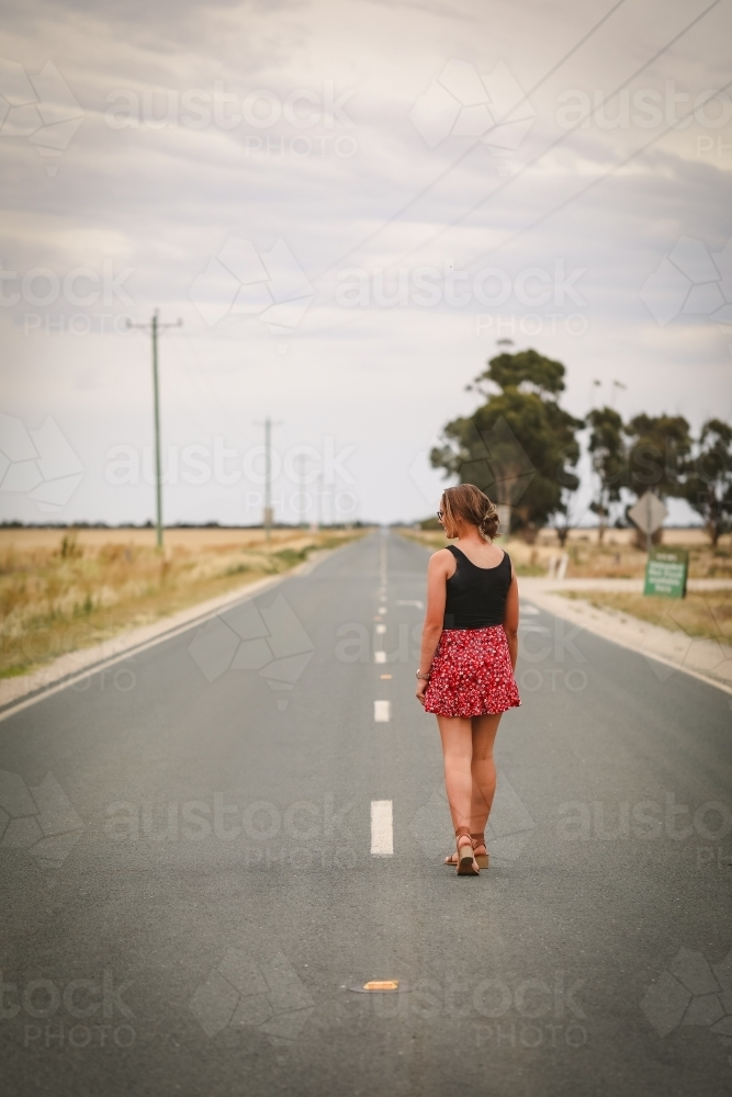 Young adult woman down empty rural road - Australian Stock Image