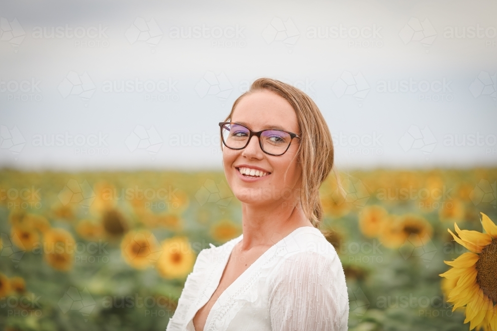 Young adult woman standing in sunflower field - Australian Stock Image