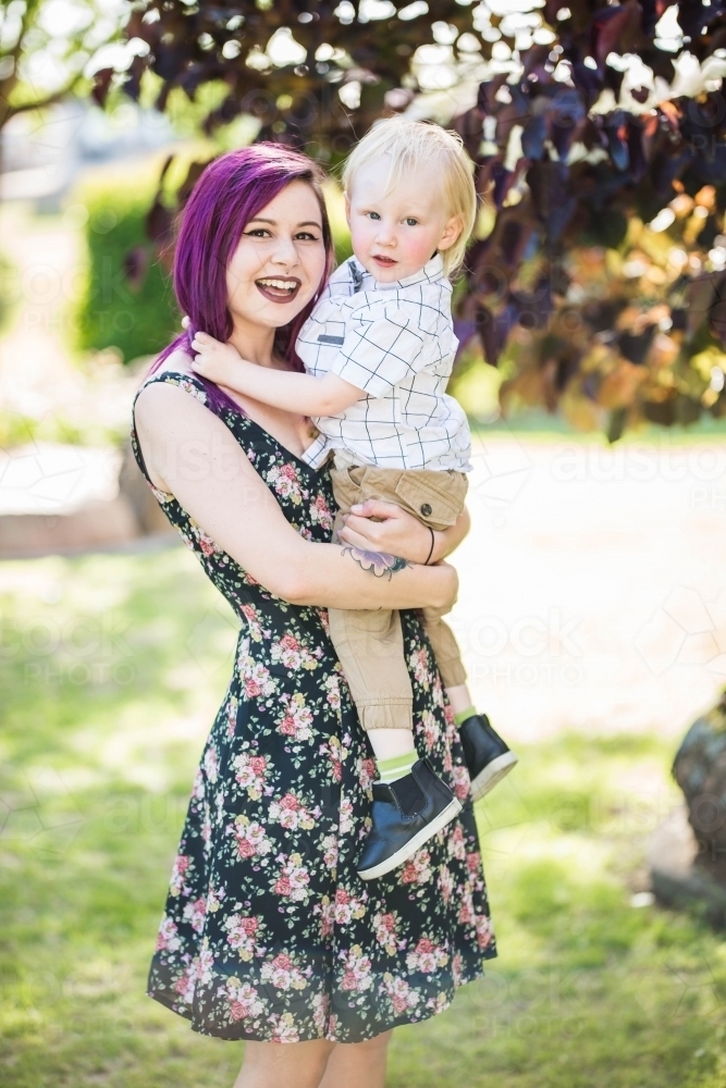 Young alternative mum holding young child with arms around neck - Australian Stock Image