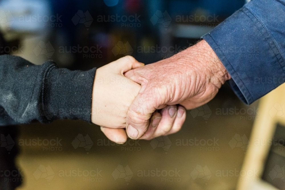 Young and old person handshake - Australian Stock Image