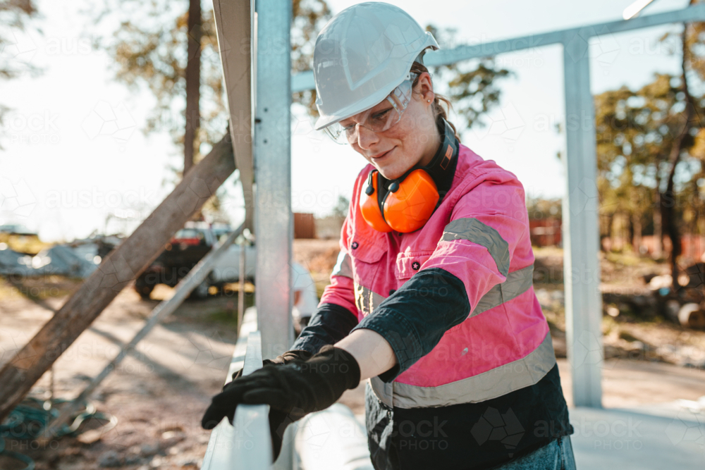 Young apprentice using a leveller on the metal framework. - Australian Stock Image