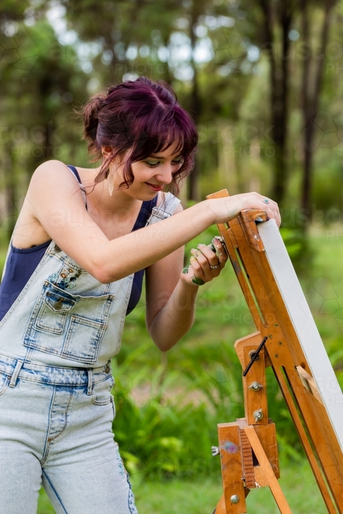 Young artist adjusting height of painting easel - Australian Stock Image