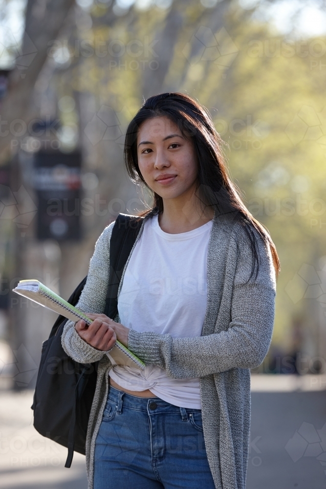 Young Asian female university student carrying study notes - Australian Stock Image