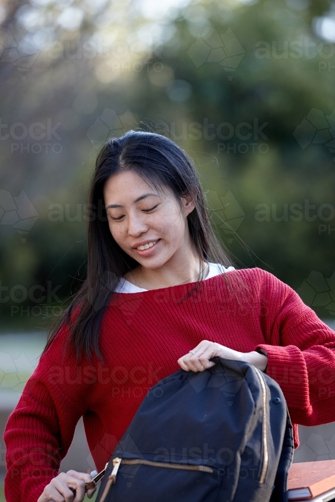 Young Asian female university student opening bag - Australian Stock Image