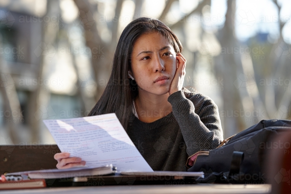 Young Asian female university student studying outdoors - Australian Stock Image