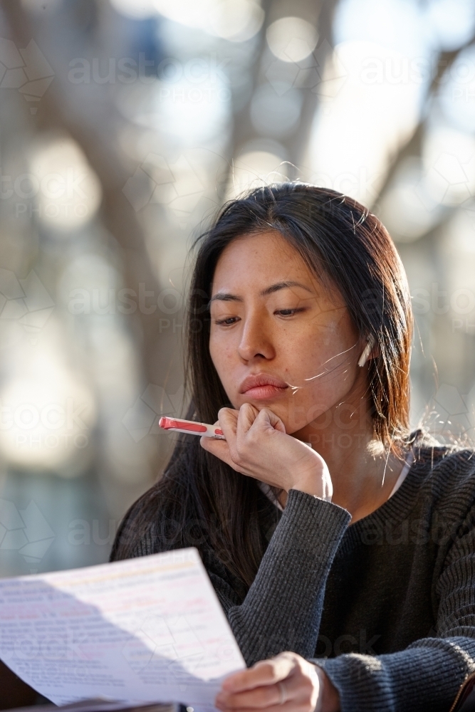 Young Asian female university student studying outdoors - Australian Stock Image