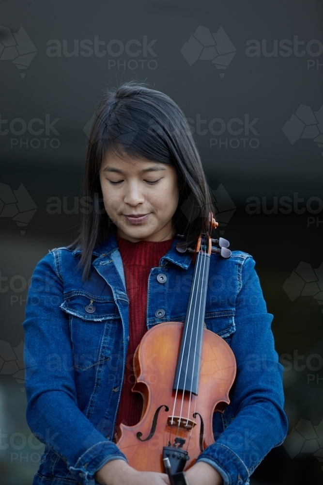 Young Asian female violin player practising outdoors - Australian Stock Image