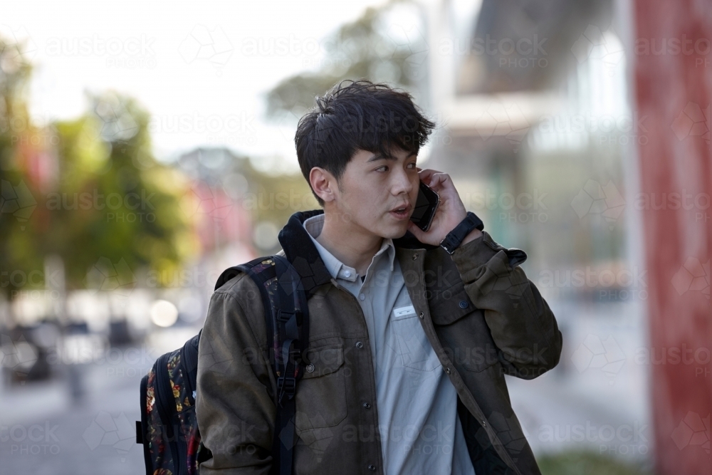 Young Asian university student talking on mobile phone - Australian Stock Image