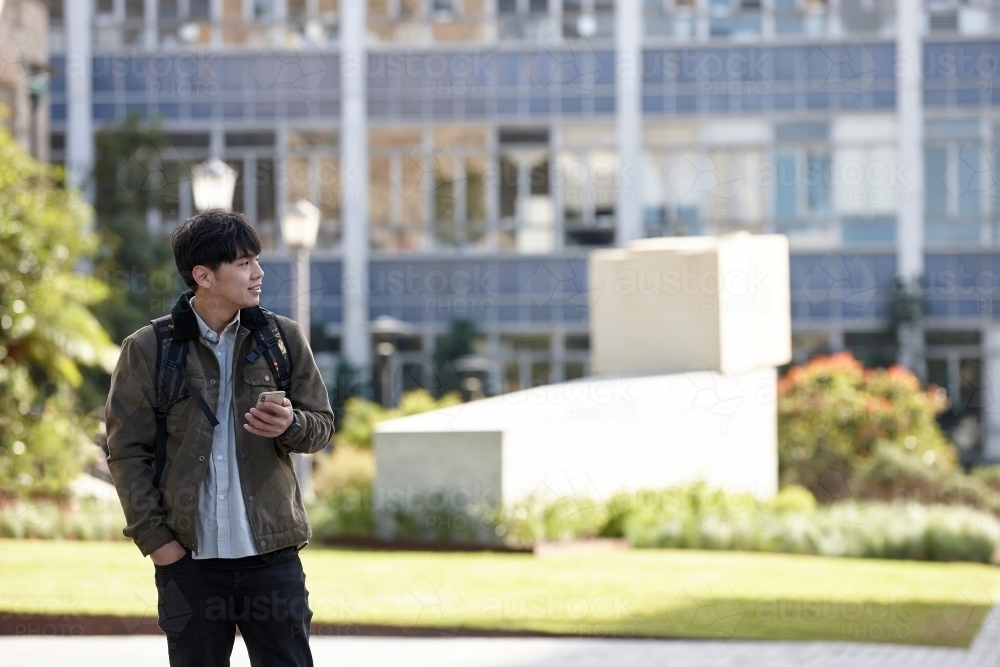 Young Asian university student using mobile phone on-campus - Australian Stock Image