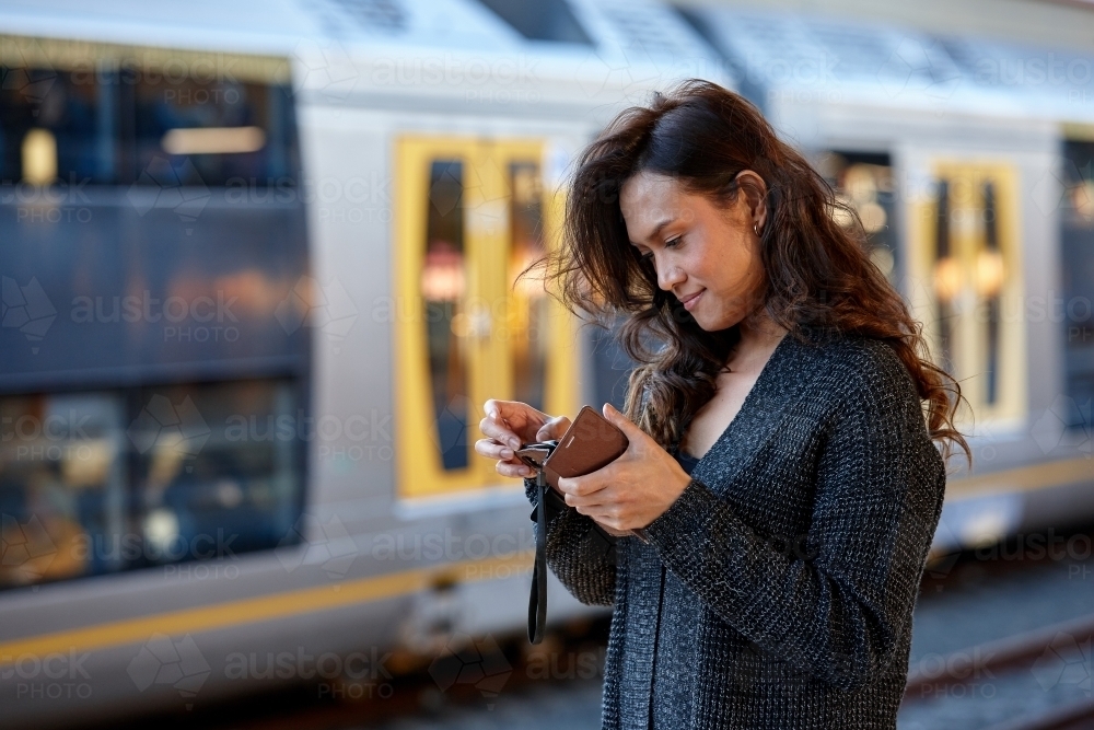 Young Asian woman checking mobile phone at train station - Australian Stock Image