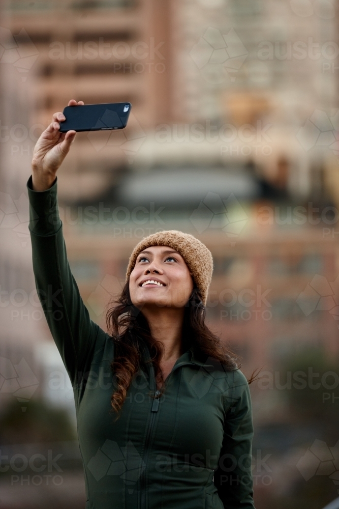 Young Asian woman taking a selfie with mobile phone in city - Australian Stock Image