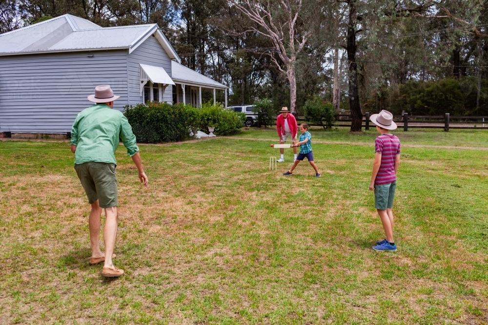 Image of Young aussie boys playing backyard cricket with dad and ...