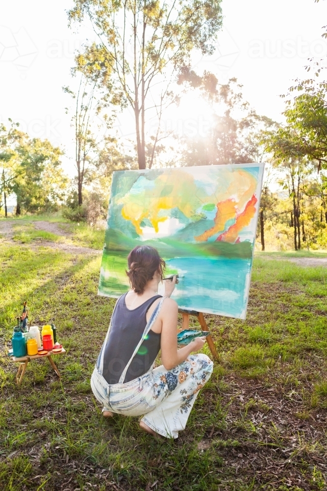 Young aussie person working on landscape painting in nature outdoors - Australian Stock Image