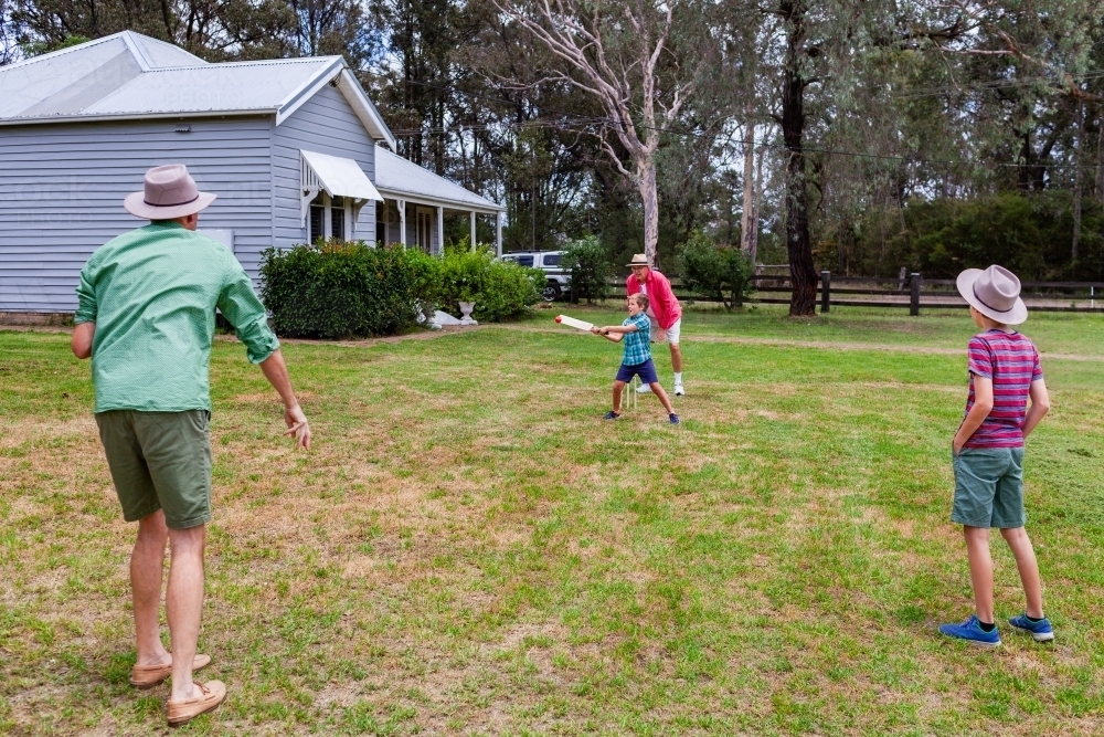 Image of Young Australian boys playing backyard cricket with dad and ...