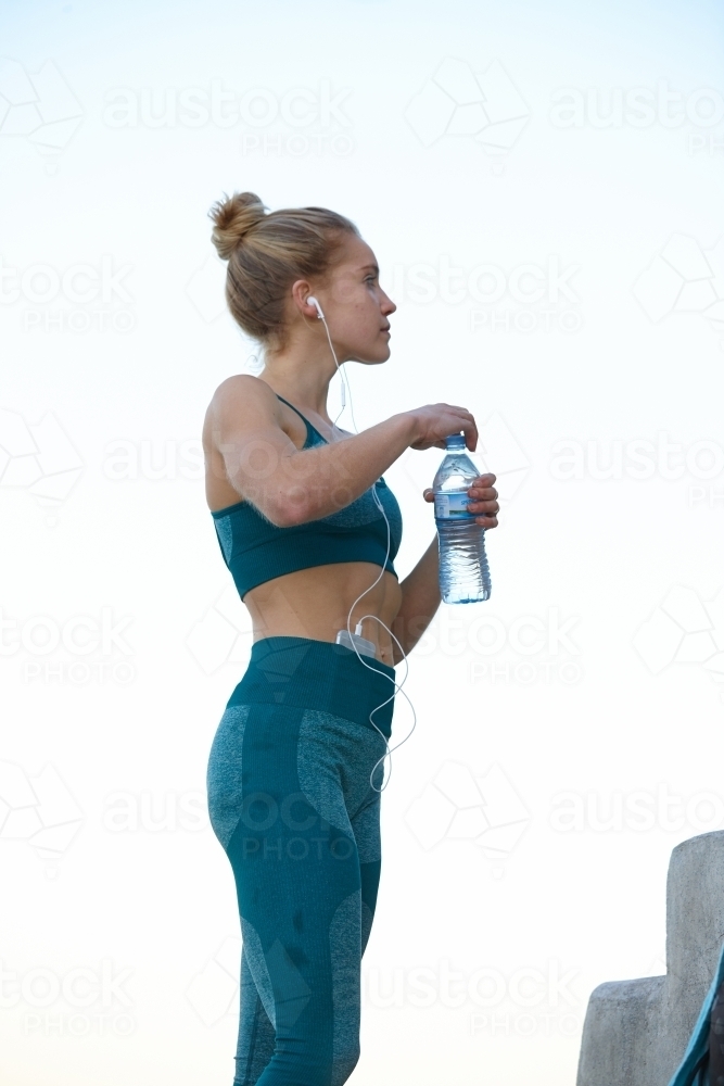 Young blonde-haired woman taking a break from training and drinking some water - Australian Stock Image