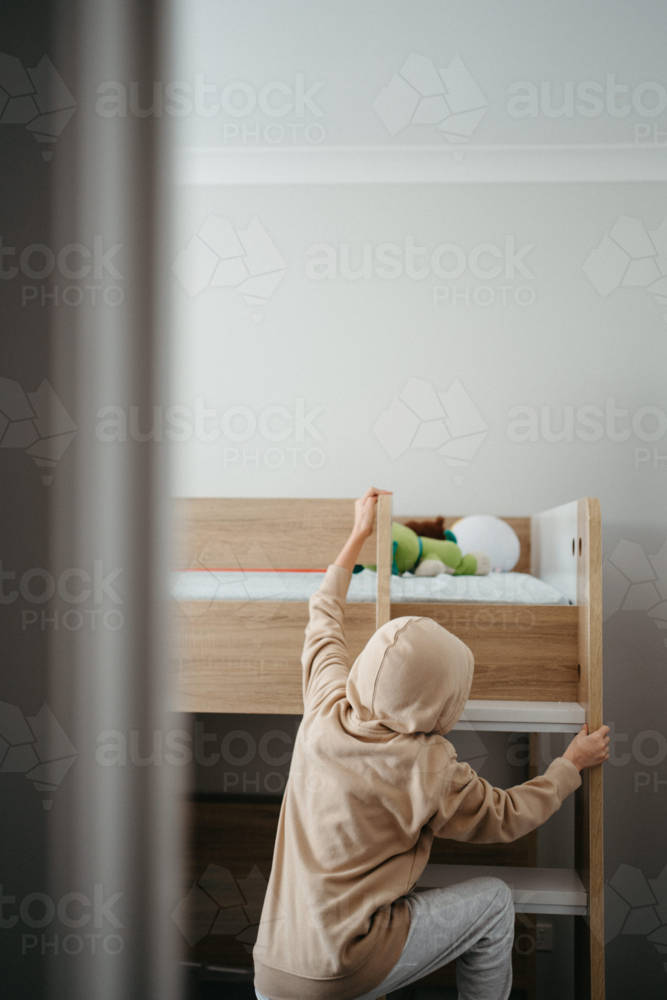 Young boy climbing up the ladder of the bunk bed. - Australian Stock Image