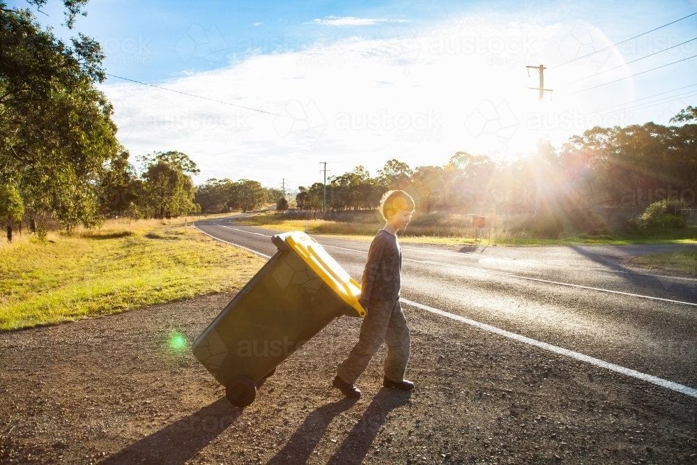 Young boy doing job taking bin across the road - Australian Stock Image