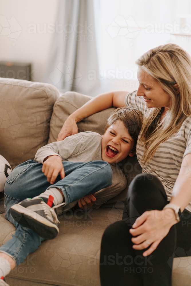 Young boy giggling while snuggling into mums side. - Australian Stock Image